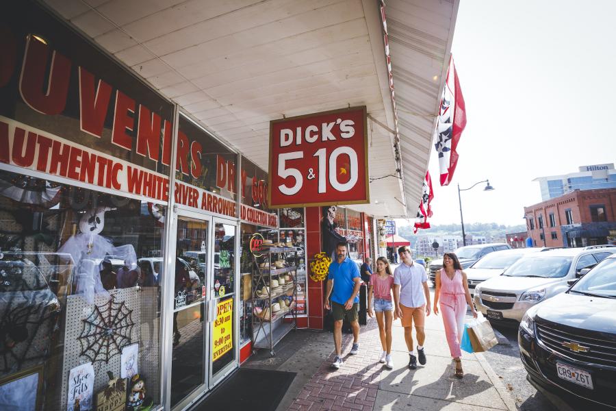 Family of four walking on the sidewalk in front of Dick's 5 & 10 shop in Downtown Branson.