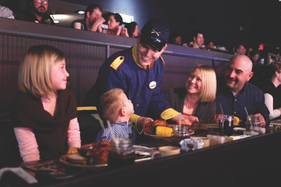 Family of four being served dinner by a waiter a Dolly Parton's Stampede Dinner Attraction in Branson.