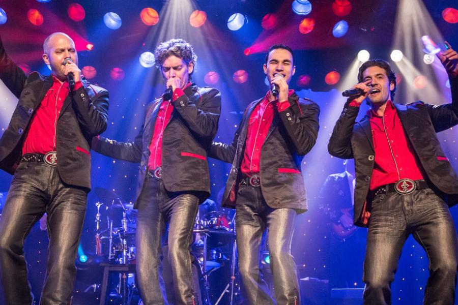 Musical group of four men singing on stage.