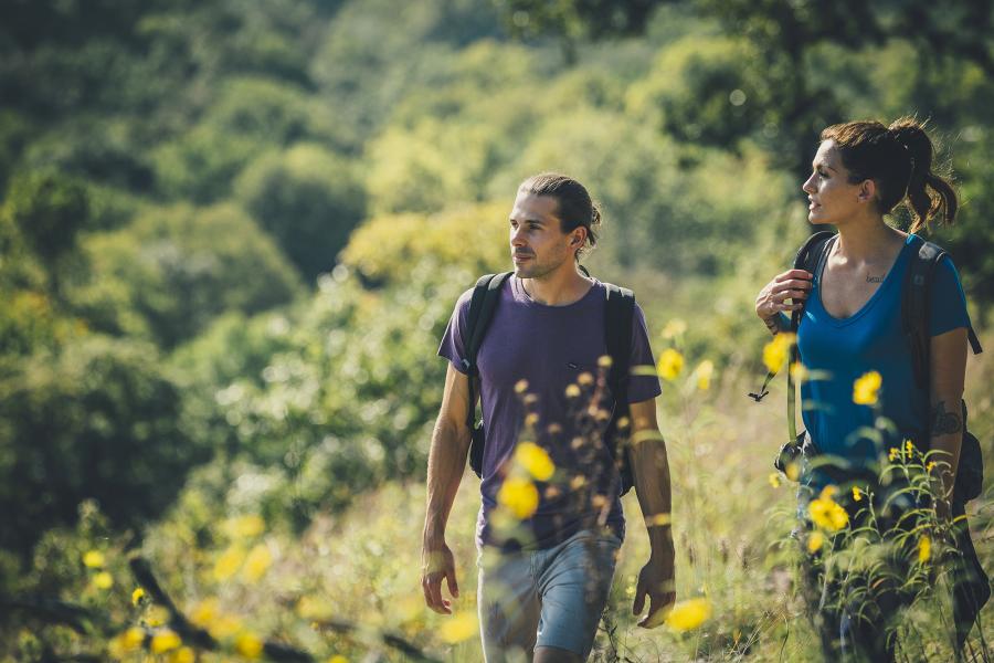 Close up of man and woman hiking with a forest in the background.