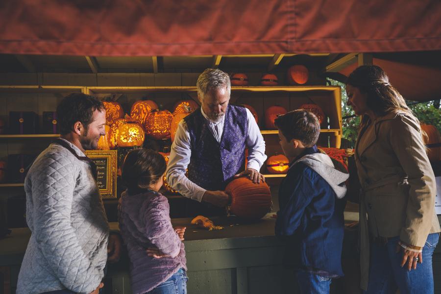 A family watching a pumpkin carver at Fall Festival at SDC