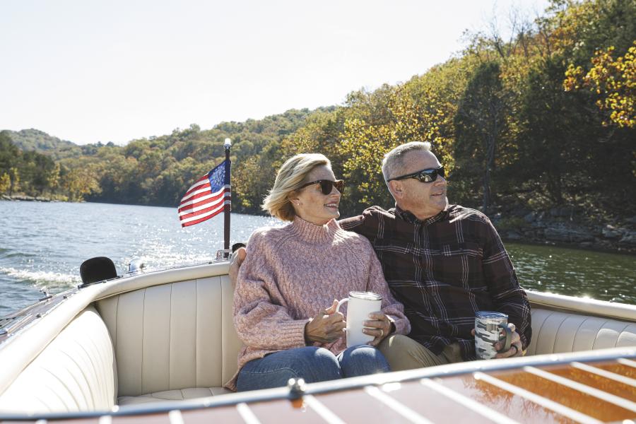 A couple riding a boat together on Table Rock Lake surrounded by a beautiful fall landscape
