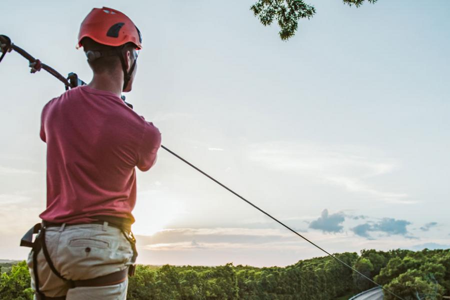 Man riding on outdoor zipline at an adventure park in Branson.