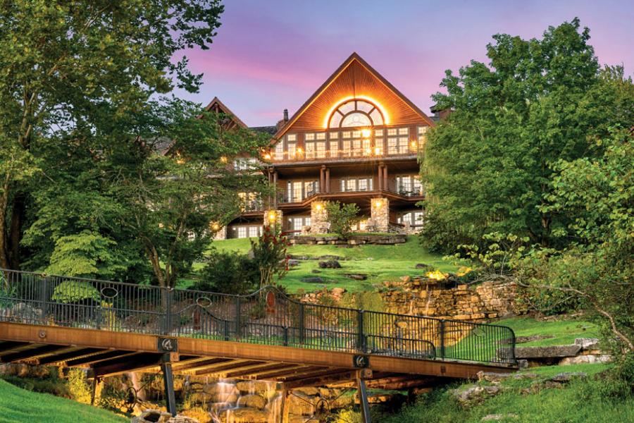 Front view of scenic log cabin hotel with waterfalls in the front lawn in the Ozark Mountains