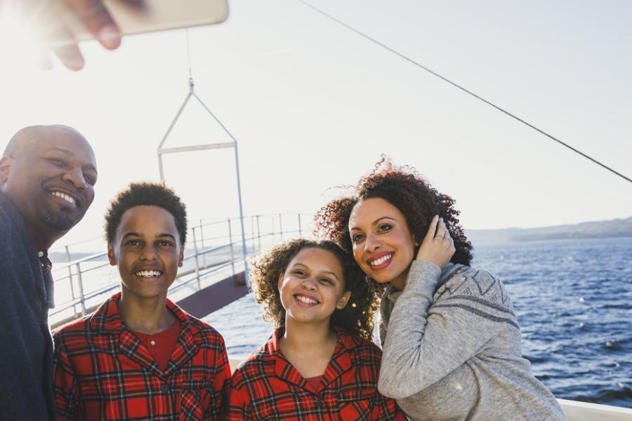 Dad and mom taking a selfie with their son and daughter who are both wearing red plaid pajamas before a morning live show performance on a boat in Branson.