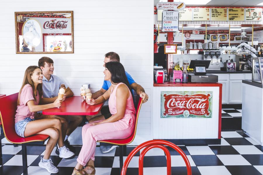 Family of four enjoying an ice cream cone at an old-time ice cream parlor in Downtown Branson.