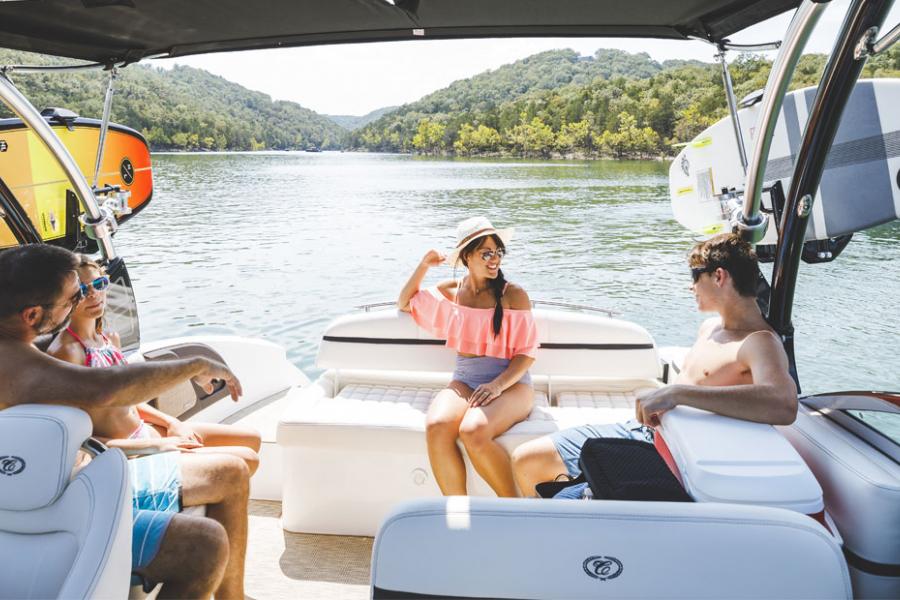 Family of four sitting on the back of a boat during summer, enjoying the Ozark Mountain scenery on a lake in Branson. 