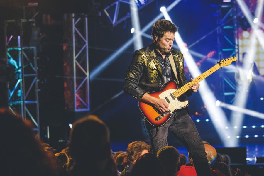Man with guitar performing on a live show stage in Branson.