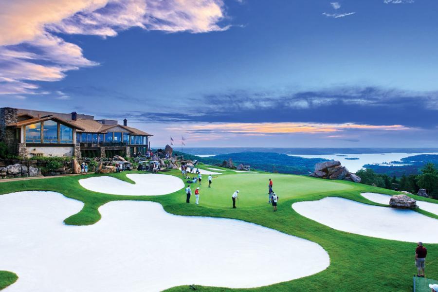 Golfers walking around green at scenic golf course on a mountain in Branson. 