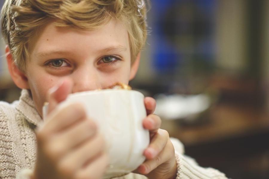 Young boy drinking hot chocolate.