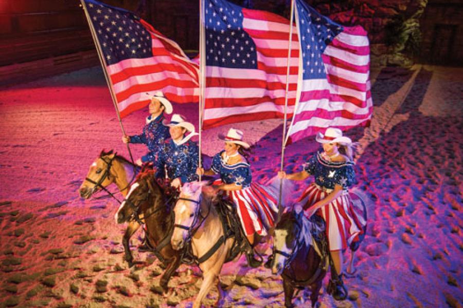 Four performers riding horses and singing in Branson show. 