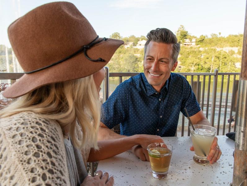 A couple smiling at one another sitting on the balcony at Cantina Laredo
