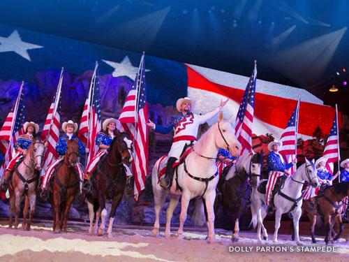 Performers riding horses and holding American flags in a Branson live show.