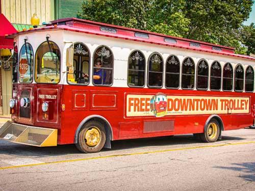 Red free trolley driving through Historic Downtown Branson.