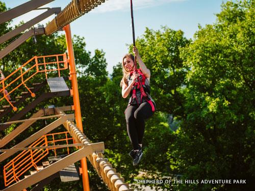 Woman climbing through outdoor ropes course in Branson.