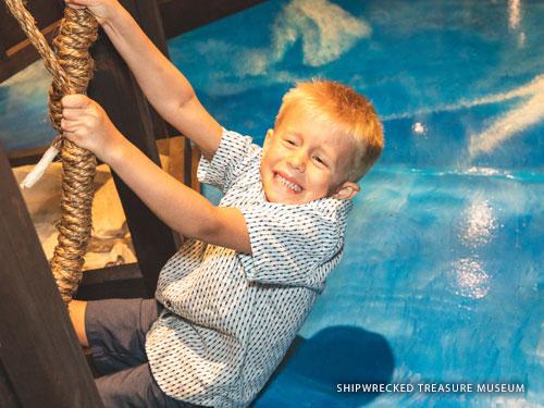 Young boy pulling on two ropes inside an interactive museum in Branson. 